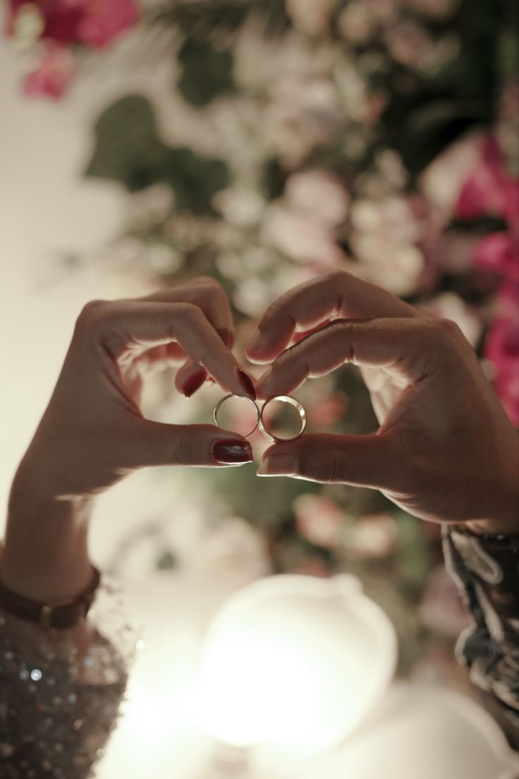 a woman making a heart shape with her hands and holding a ring in front of her face