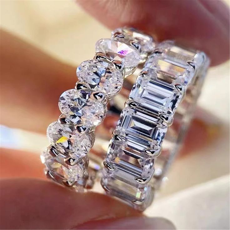 a close up of a person's hand holding a ring with diamonds on it