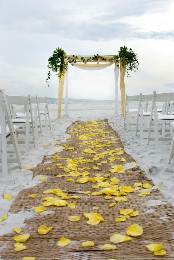 the aisle is decorated with yellow petals and greenery for an outdoor ceremony at the beach