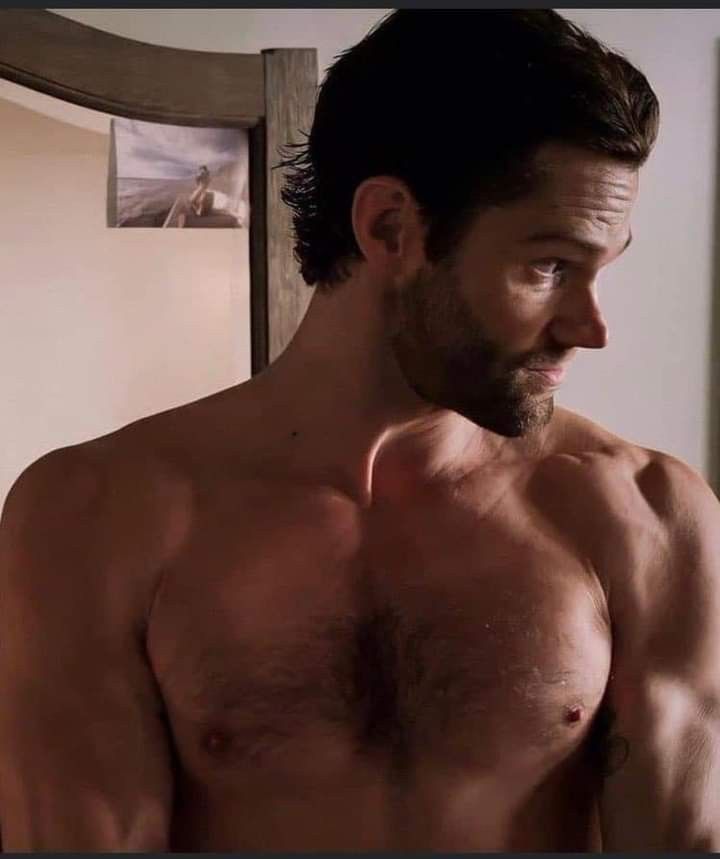 a shirtless man standing in front of a mirror