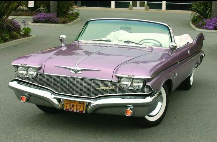 an old purple car parked in front of a building