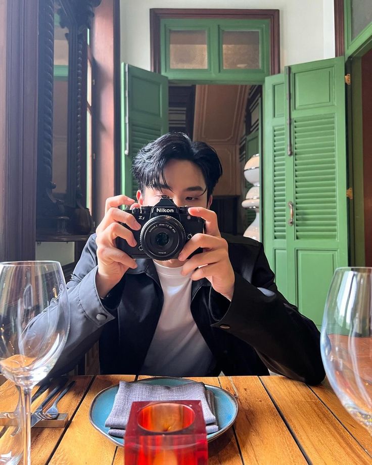 a man sitting at a table taking a photo with a camera in front of him