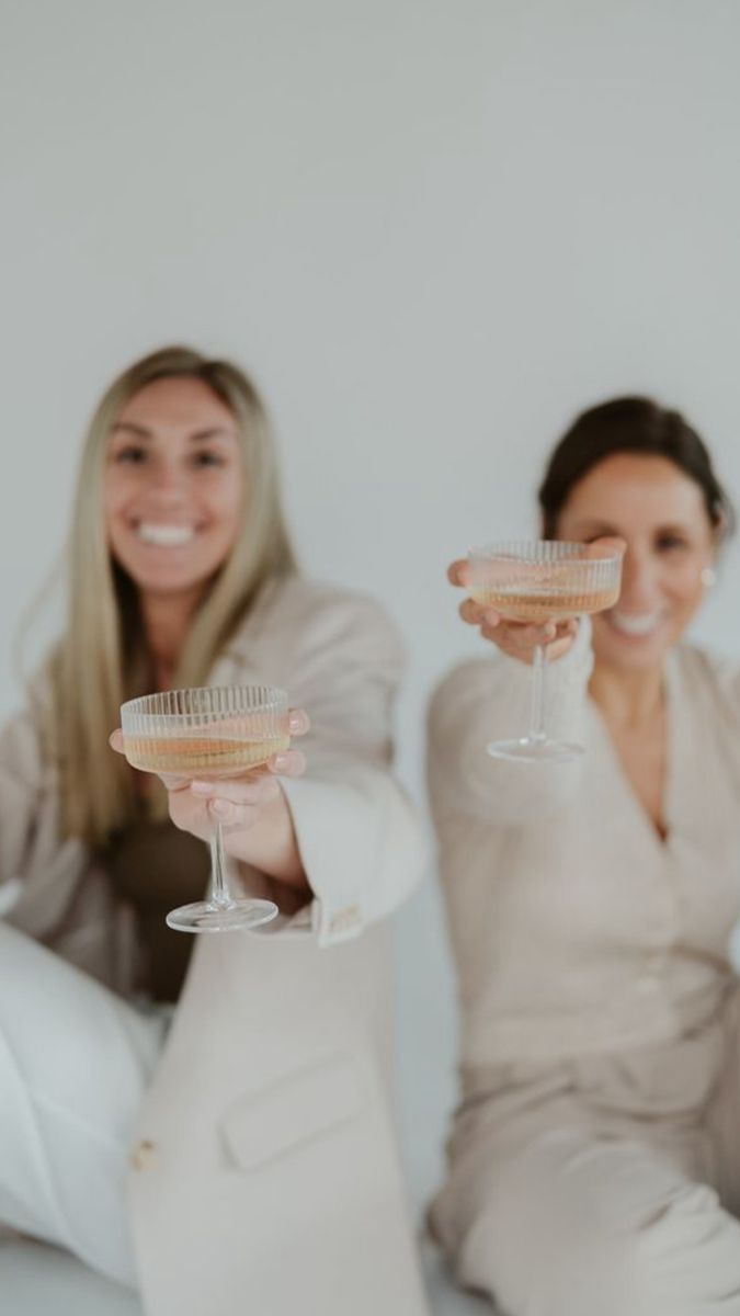 two women sitting on the floor holding wine glasses