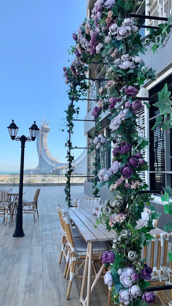 an outdoor dining area with wooden tables and chairs covered in purple flowers on the outside