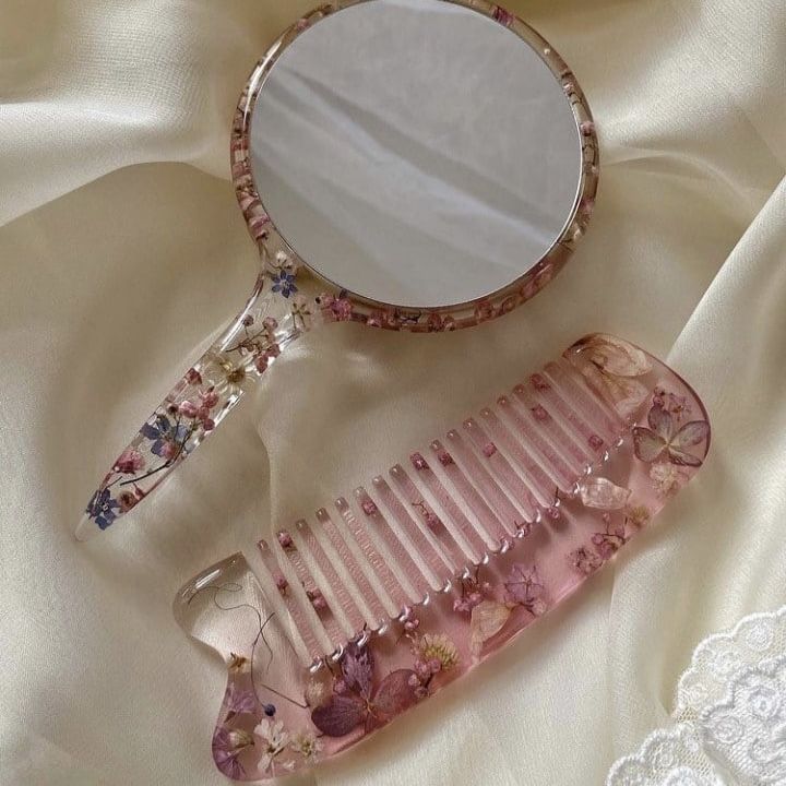 a pink comb and mirror sitting on top of a white cloth