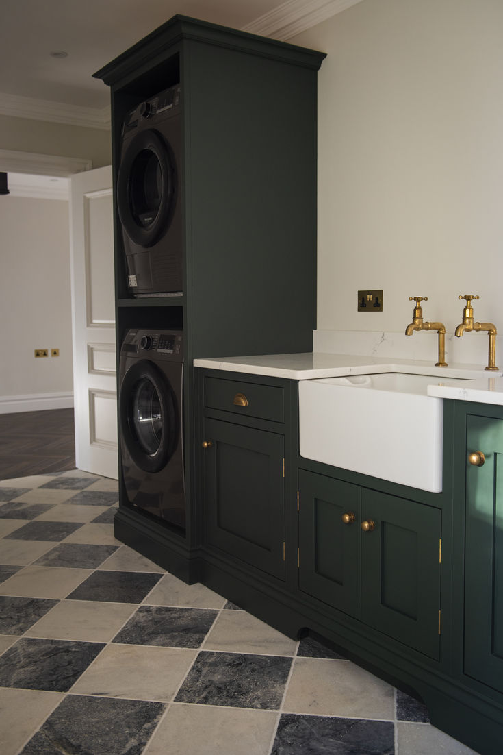 a washer and dryer are in the corner of this laundry room with green cabinets