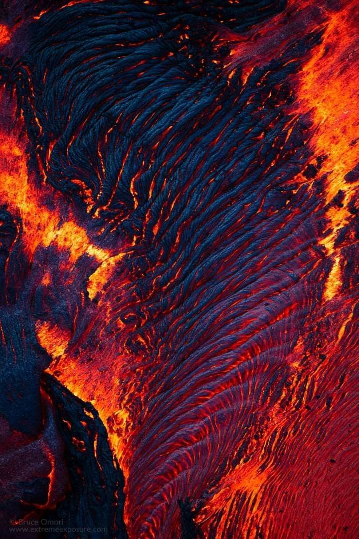 an aerial view of lava in the ocean with red and blue colors on it's surface