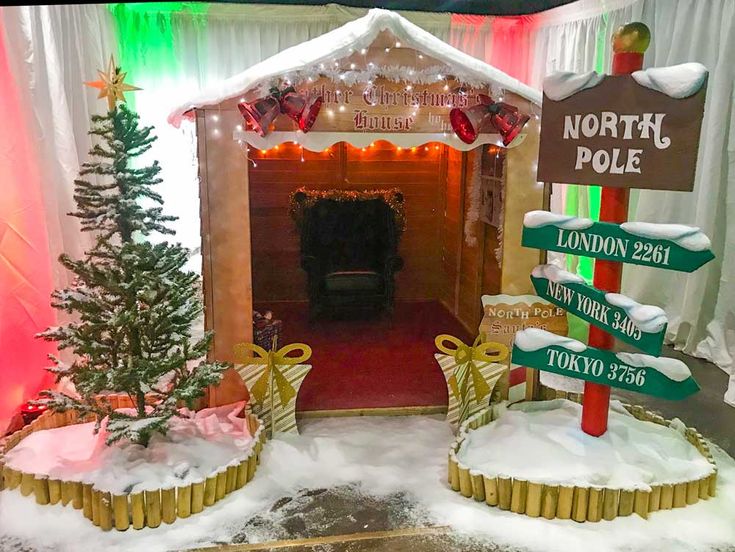 a christmas display in the shape of a small cabin with signs and decorations on it