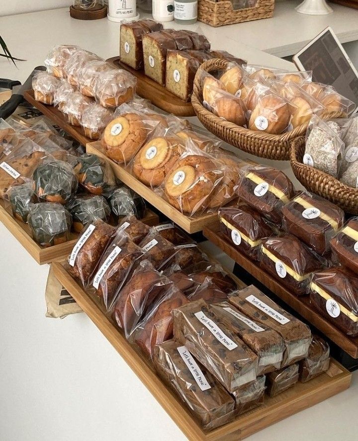 breads and pastries are on display at a bakery counter with laptops in the background