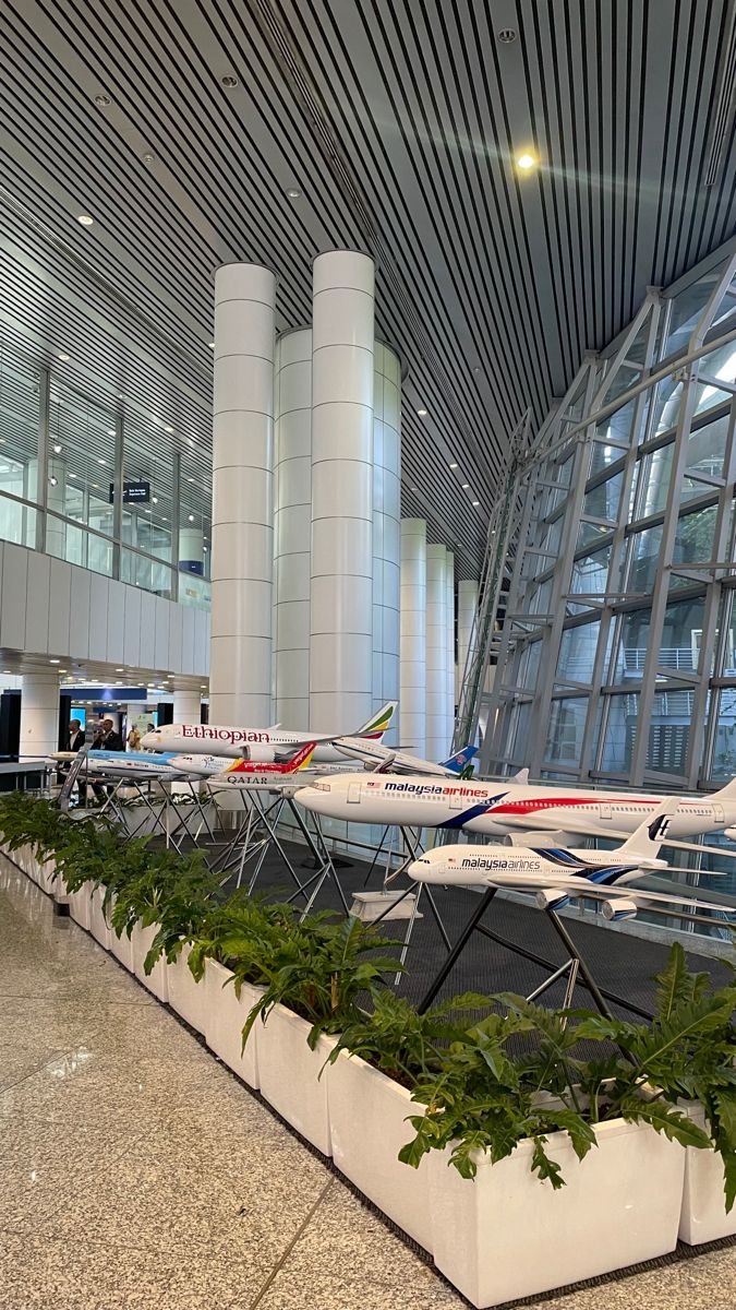 an airport terminal with several planes parked in front of the glass windows and plants growing on the concrete planter