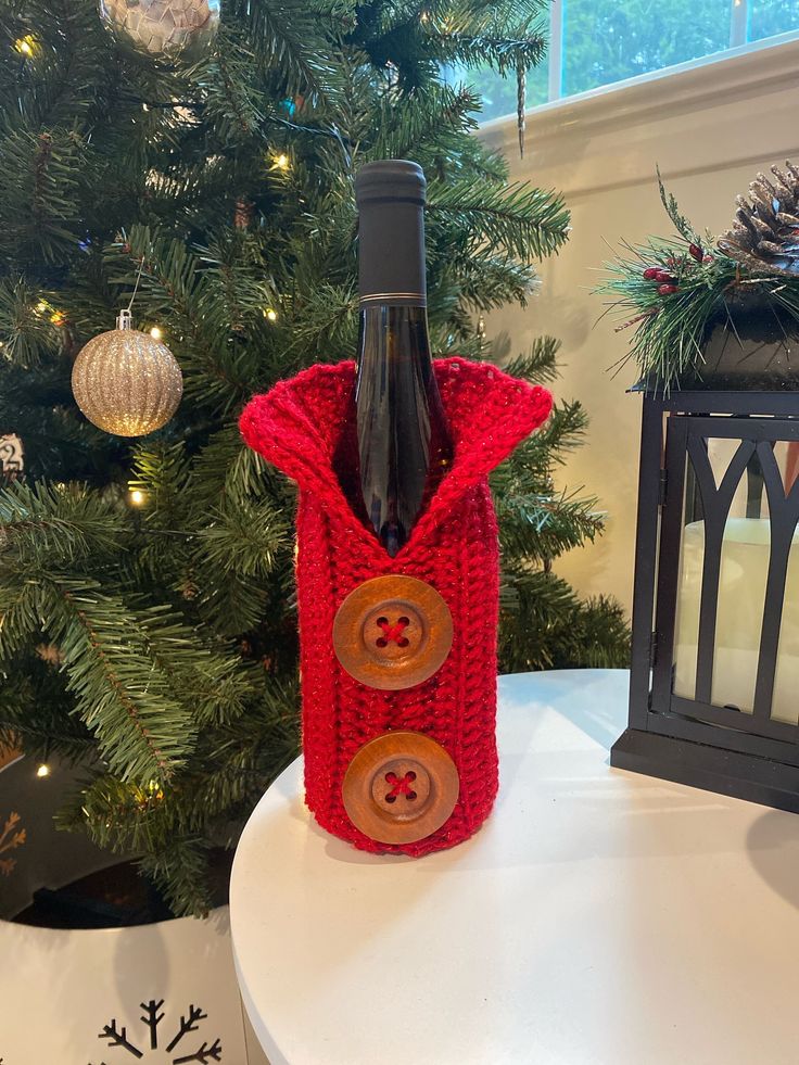 a bottle of wine sitting on top of a table next to a christmas tree with decorations