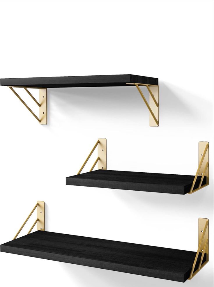 three black shelves with gold brackets on them