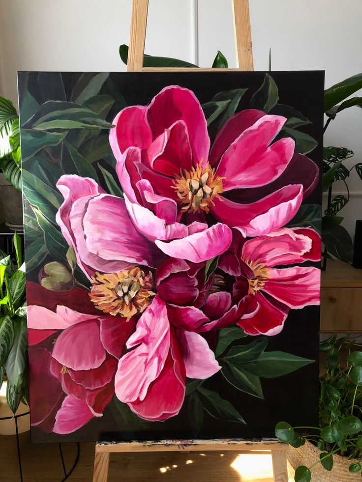 a painting of pink flowers on a easel in front of a potted plant