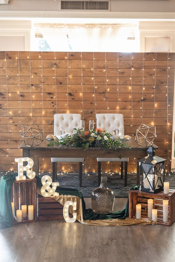 a dining room table with candles and decorations on the side, surrounded by string lights