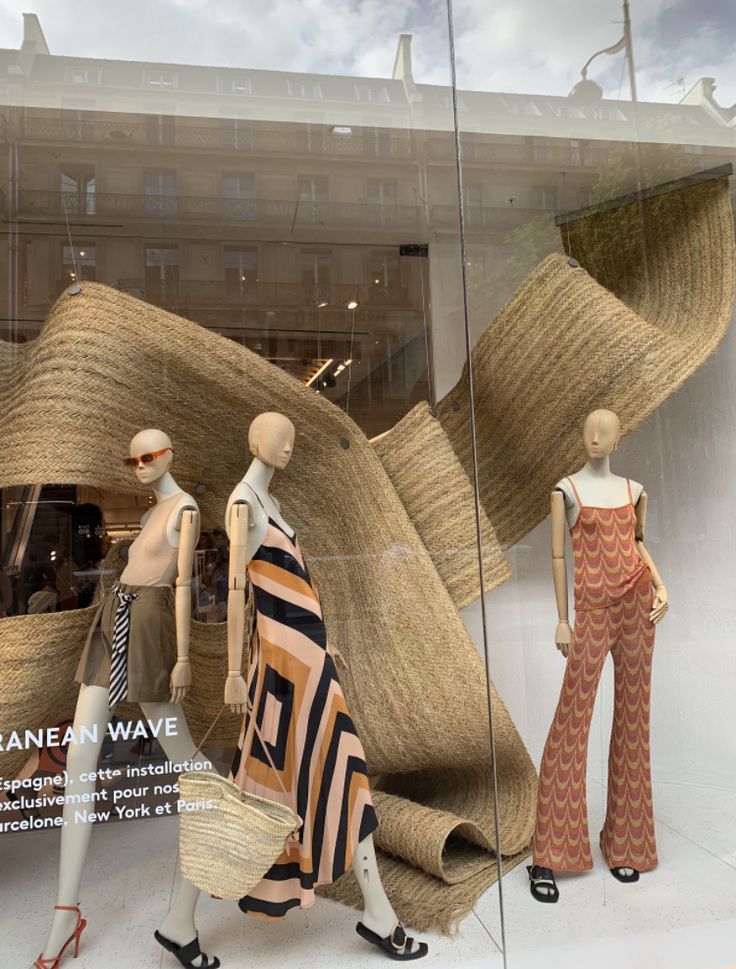 three mannequins dressed in different patterns and sizes walking past a window display