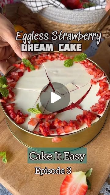 a cake with strawberries on it being cut into pieces by someone using a knife