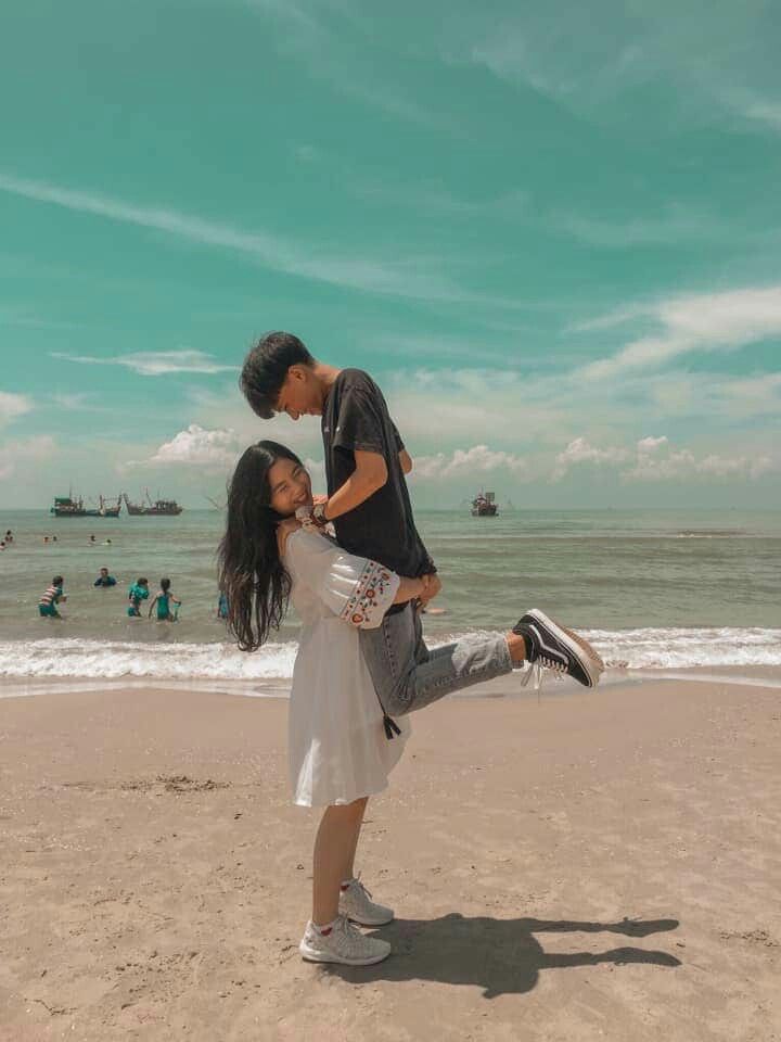 a man and woman kissing on the beach