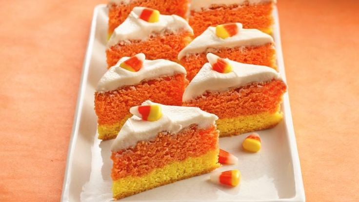 several pieces of cake on a white plate with candy corn kernels around the edges