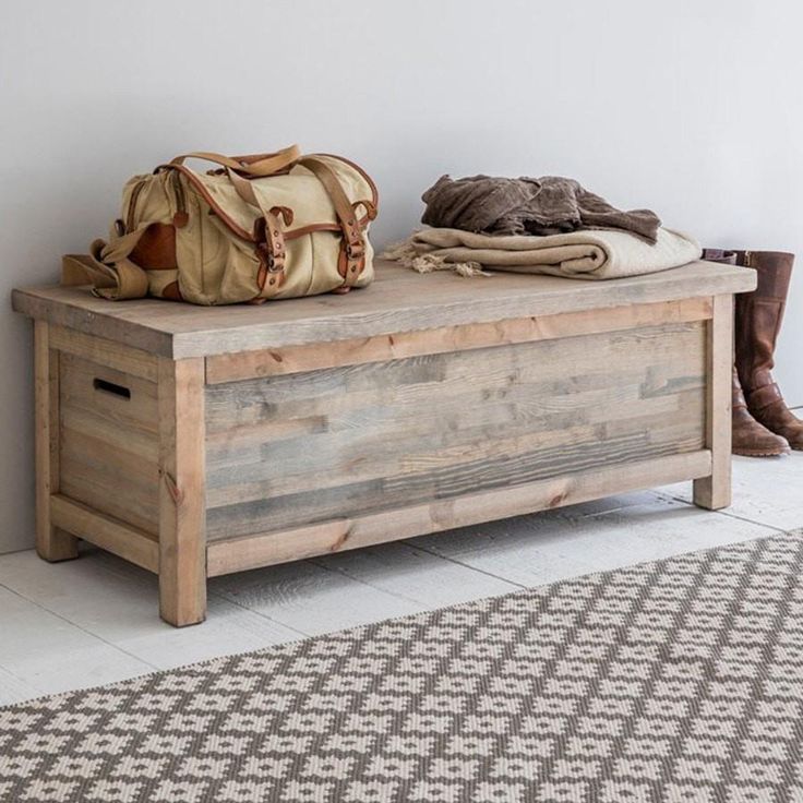 a wooden bench sitting on top of a white floor next to a rug and purse