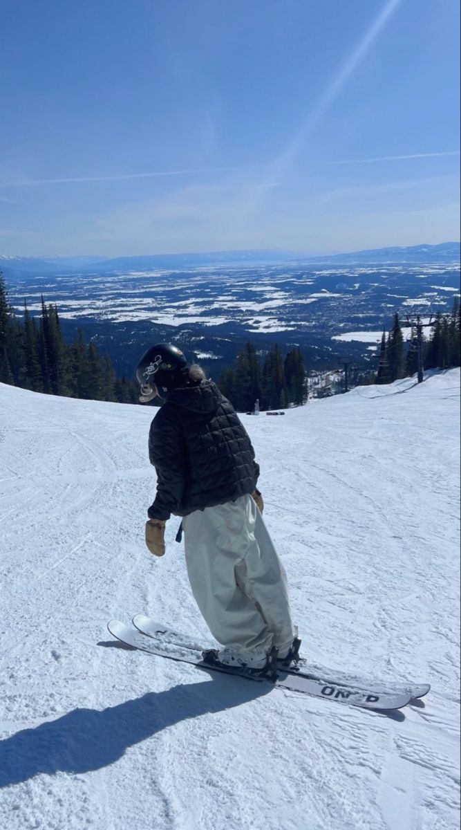 a man riding skis down the side of a snow covered slope with trees in the background