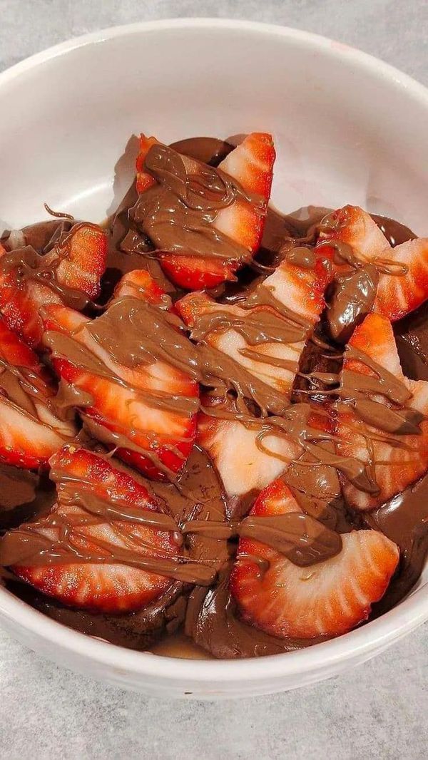 a white bowl filled with chocolate and sliced strawberries