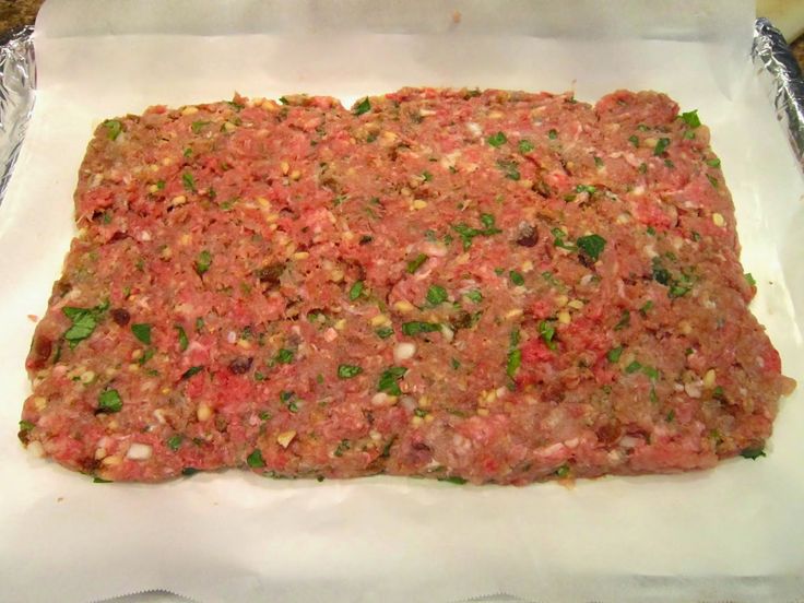 raw ground meat on a baking sheet ready to go into the oven