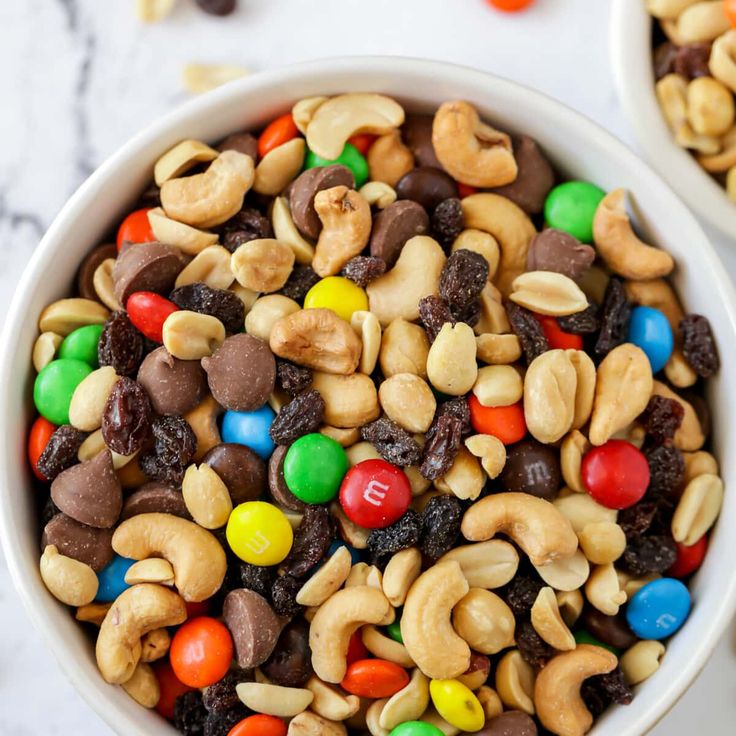 two white bowls filled with m & m's cereal and candy coated candies