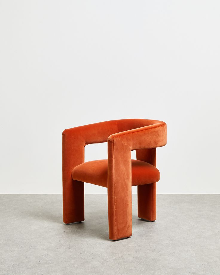 an orange chair sitting on top of a cement floor