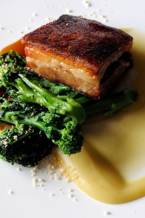 a white plate topped with meat and broccoli covered in gravy next to sauce