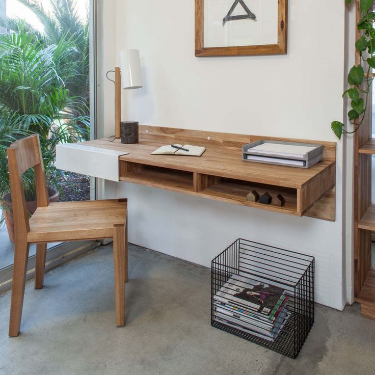 a desk and chair in front of a window with plants on the windowsill next to it