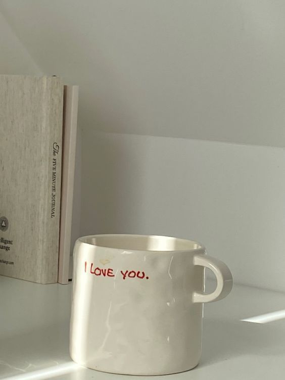 a white coffee mug sitting next to a book