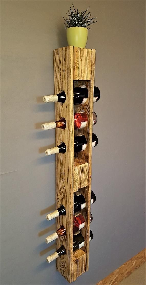 a wooden wine rack with several bottles in it and a potted plant on top