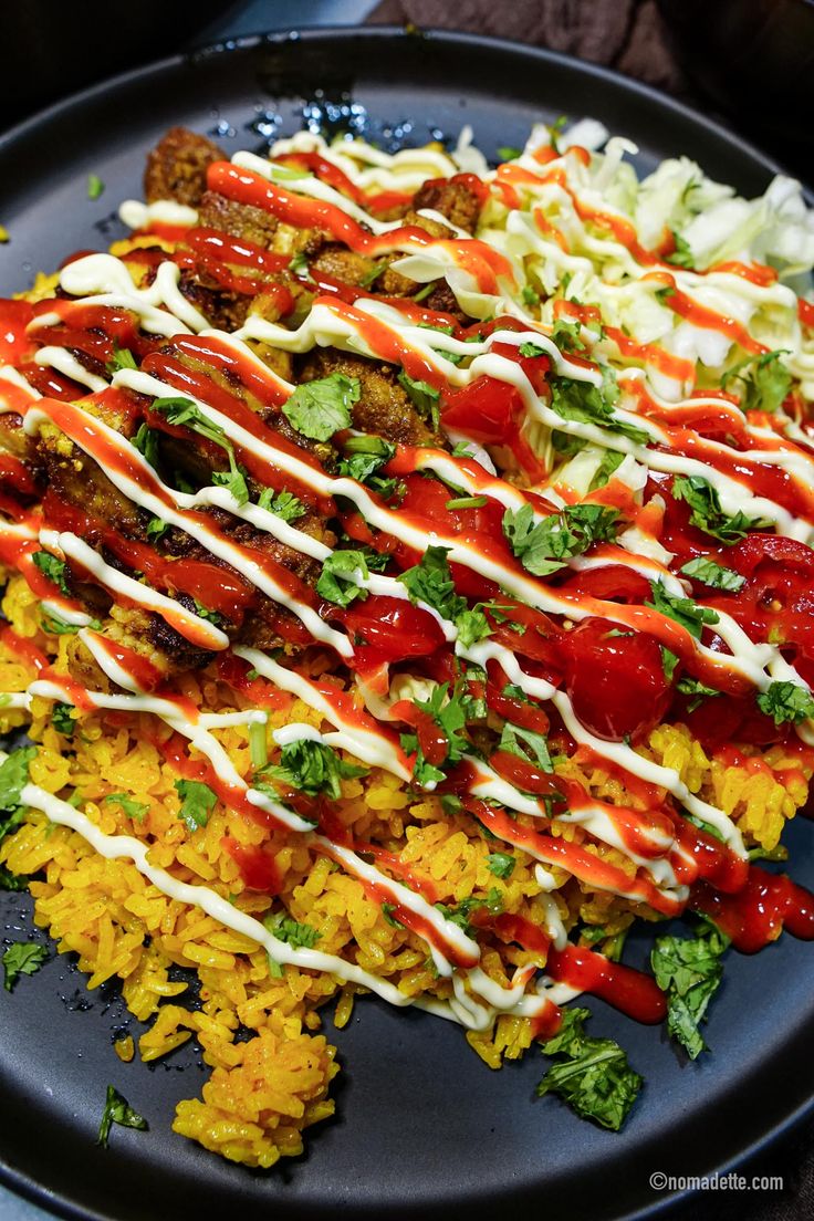 a plate with rice, meat and vegetables covered in sauces on top of it