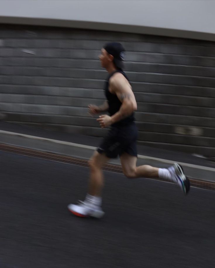 a man running down the street in shorts and a tank top with no shirt on