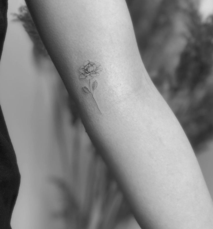 a woman's arm with a single flower tattoo on the left side of her arm