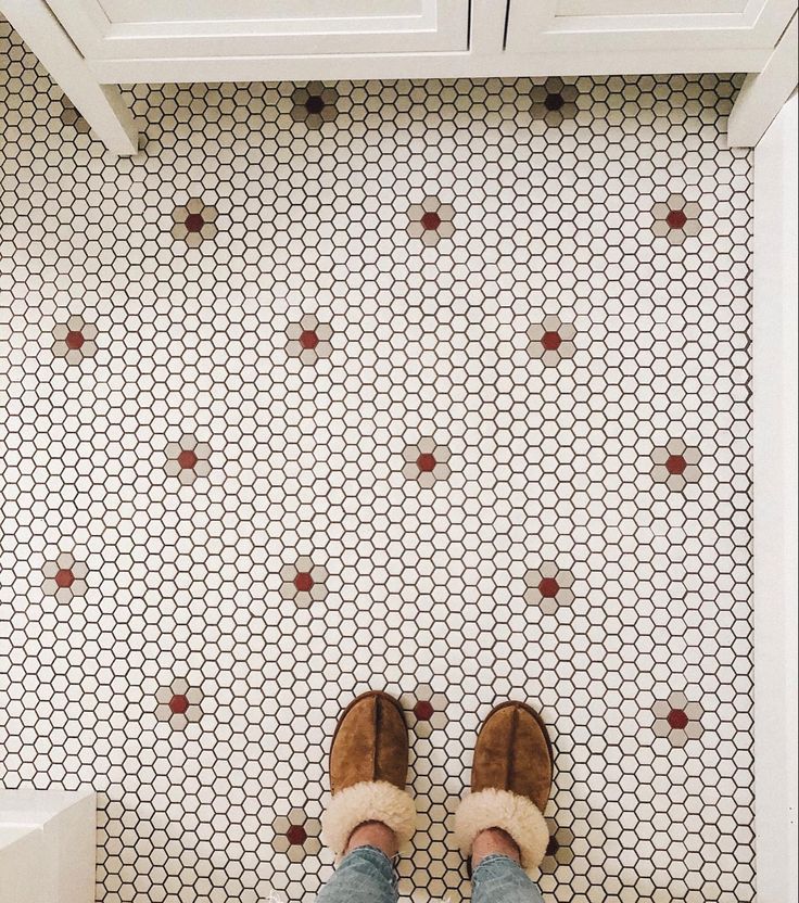 a person standing on a tiled floor with their feet up in the air and wearing slippers