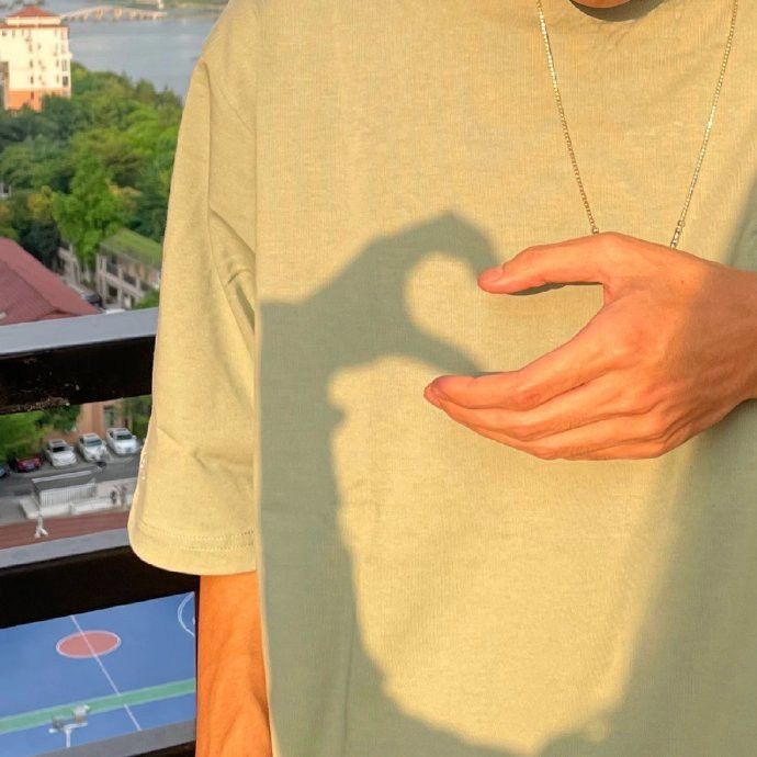 a man holding his hand out in front of him with a shadow on the shirt