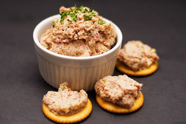 crackers with tuna and parsley in a white bowl on a black tablecloth