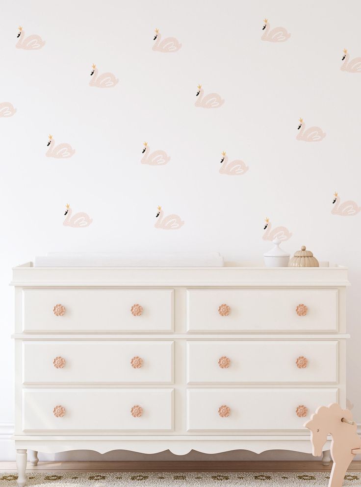 a white dresser sitting next to a wall with pink flamingos on it