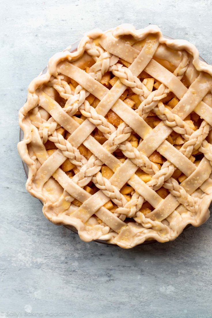 an uncooked pie with latticed crust on a gray surface, top view