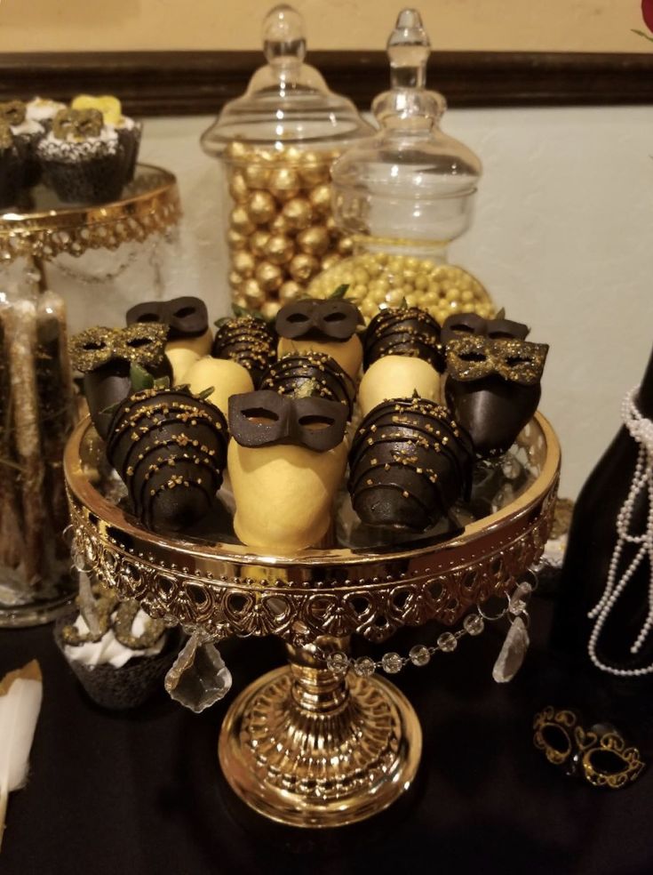 there are many desserts on the table with gold and black decorations in front of them