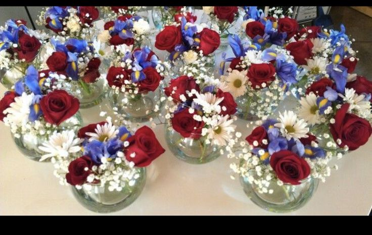 red, white and blue flowers are in vases on a table with other flowers