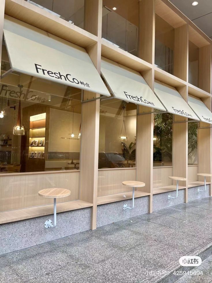 an empty sidewalk in front of a restaurant with benches and tables outside the window,