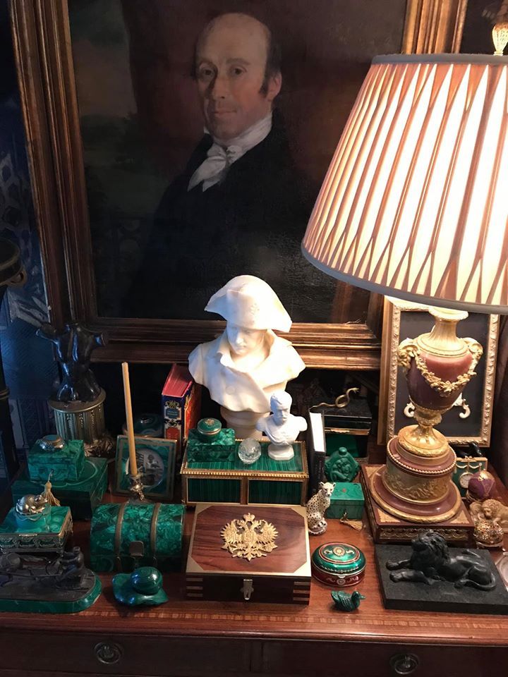 a table topped with lots of antiques and a lamp