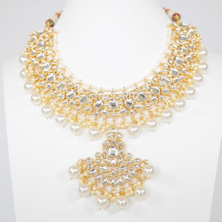 The Amaya Jewelry Set will add elegance to your look. With High-Quality Kundan, this piece is perfect to turn heads this festive season. Specifications Materials used: kundan, pearls, gold plating At Romikas, we pride ourselves on the craftsmanship and high quality of our jewelry, designed to enhance your natural beauty. Please contact us with any questions. Formal Bridal Necklace In Silver With Tilla, Formal Bridal Necklace With Tilla In Silver, Formal Silver Bridal Necklace With Tilla Detail, Formal Silver Bridal Necklace With Tilla, Elegant Chandbali Jeweled Necklace, Elegant Jeweled Chandbali Necklace, Traditional Silver Jeweled Jewelry, Festive Elegant Tilla Necklace, Elegant Jeweled Kundan Chandbali Necklace