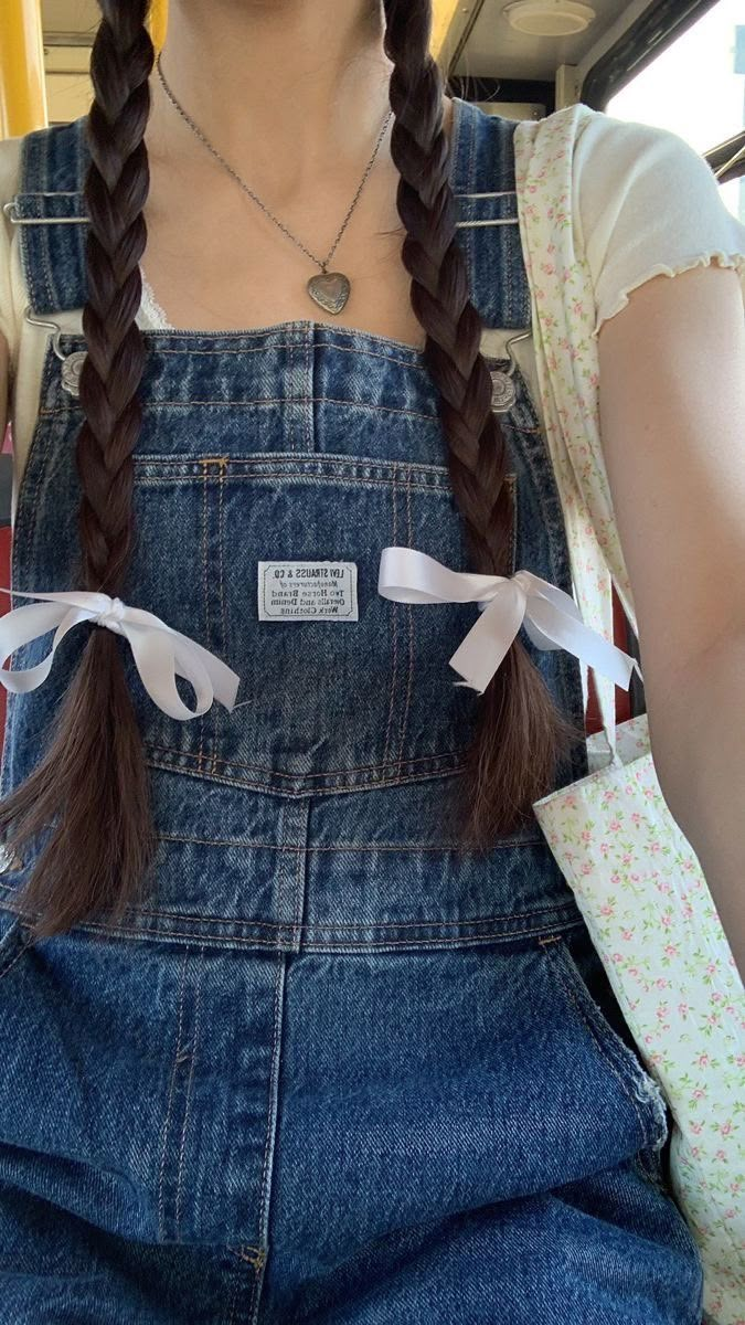 a woman with long braids wearing overalls on a bus