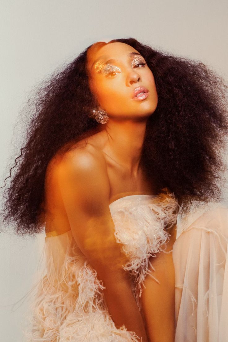 a woman with long hair wearing a white dress and gold makeup is posing for the camera