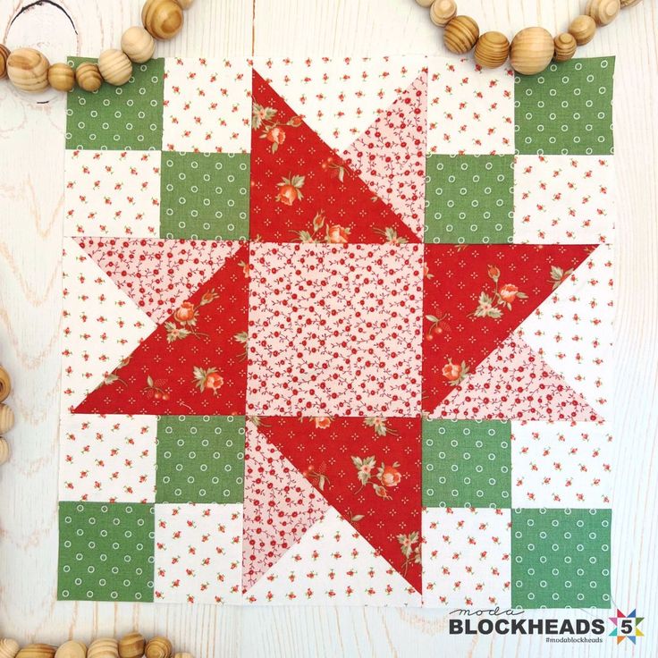 a red and green quilted star on a white wooden surface with beads around it