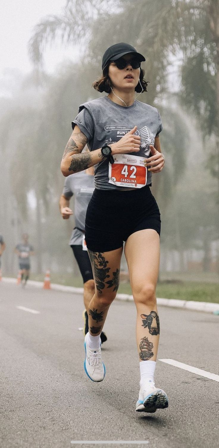 a woman running in a marathon with tattoos on her arm