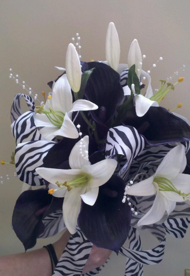 a bouquet of white and black flowers in someone's hand